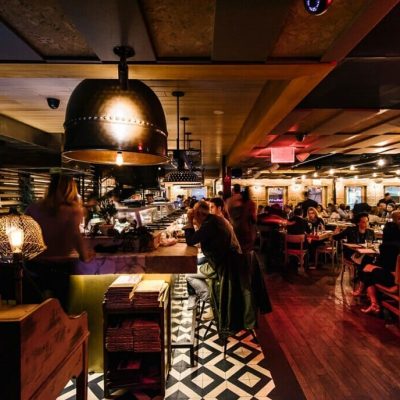 Bustling restaurant interior with geometric tile bar area, pendant lights, and warm dining ambiance