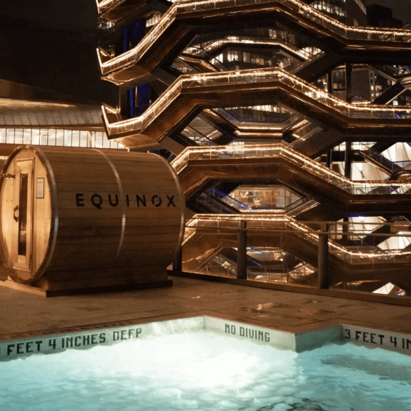 Rooftop pool and barrel sauna labeled Equinox at night with illuminated Vessel in Hudson Yards background
