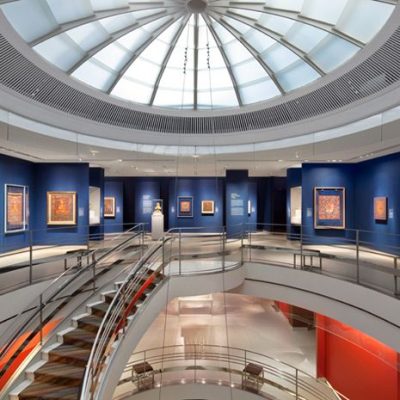 Rubin Museum of Art interior with glass dome ceiling, blue gallery walls, central staircase, and red accents