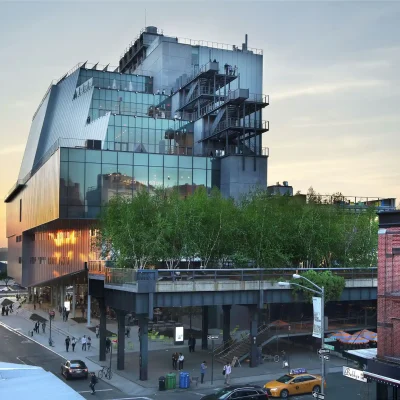 Whitney Museum at sunset with glass terraces, High Line trees, and street scene with yellow taxi