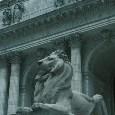 Close-up view of the New York Public Library’s stone facade, featuring carved statues and engraved text honoring the Astor Library above ornate architectural detailing.