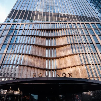 Equinox skyscraper with wave-like glass facade and branded entrance, evoking luxury, movement, and urban prestige
