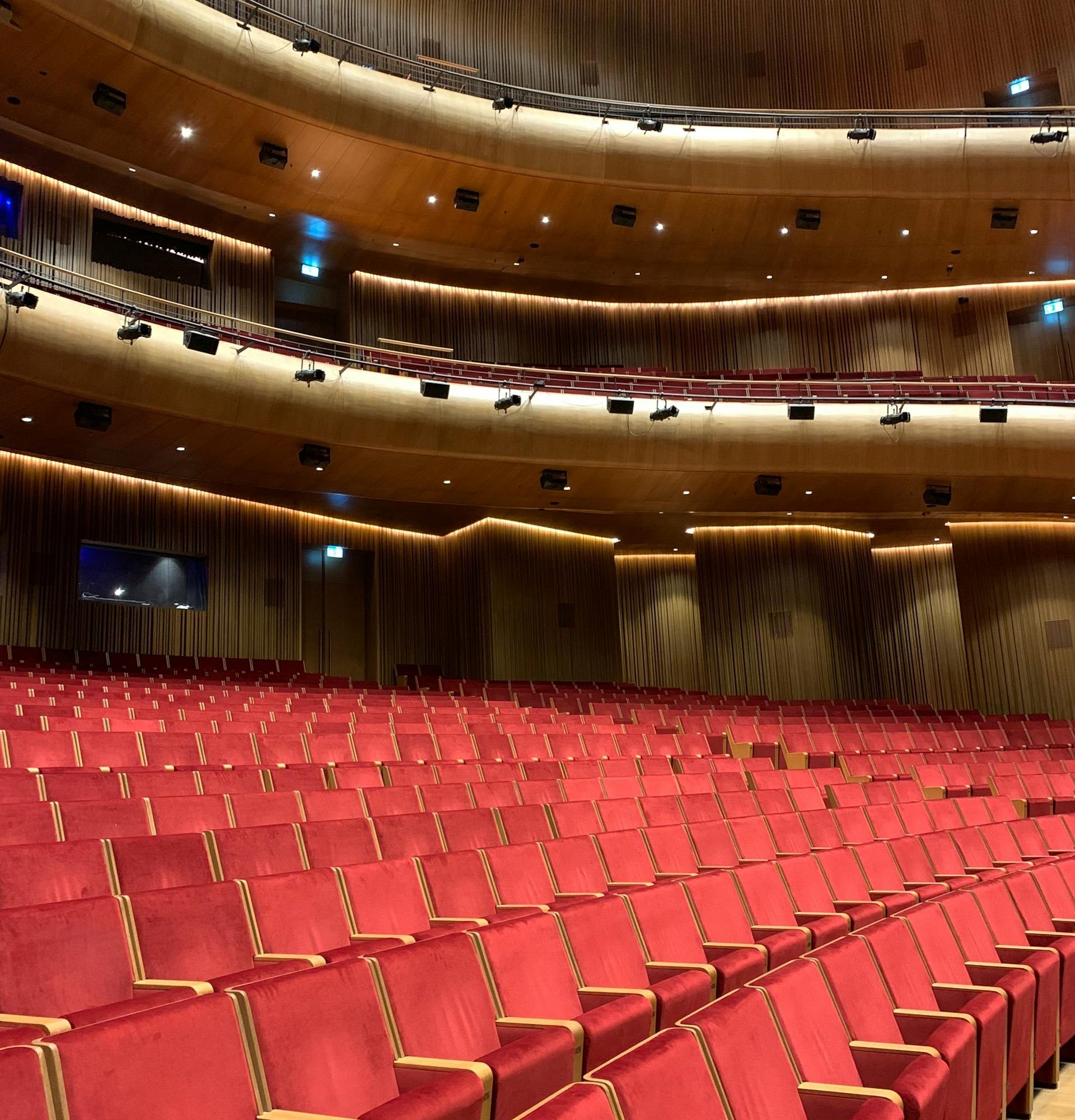 Interior of Lincoln Center theater with rows of red seats and curved wood balconies in New York City