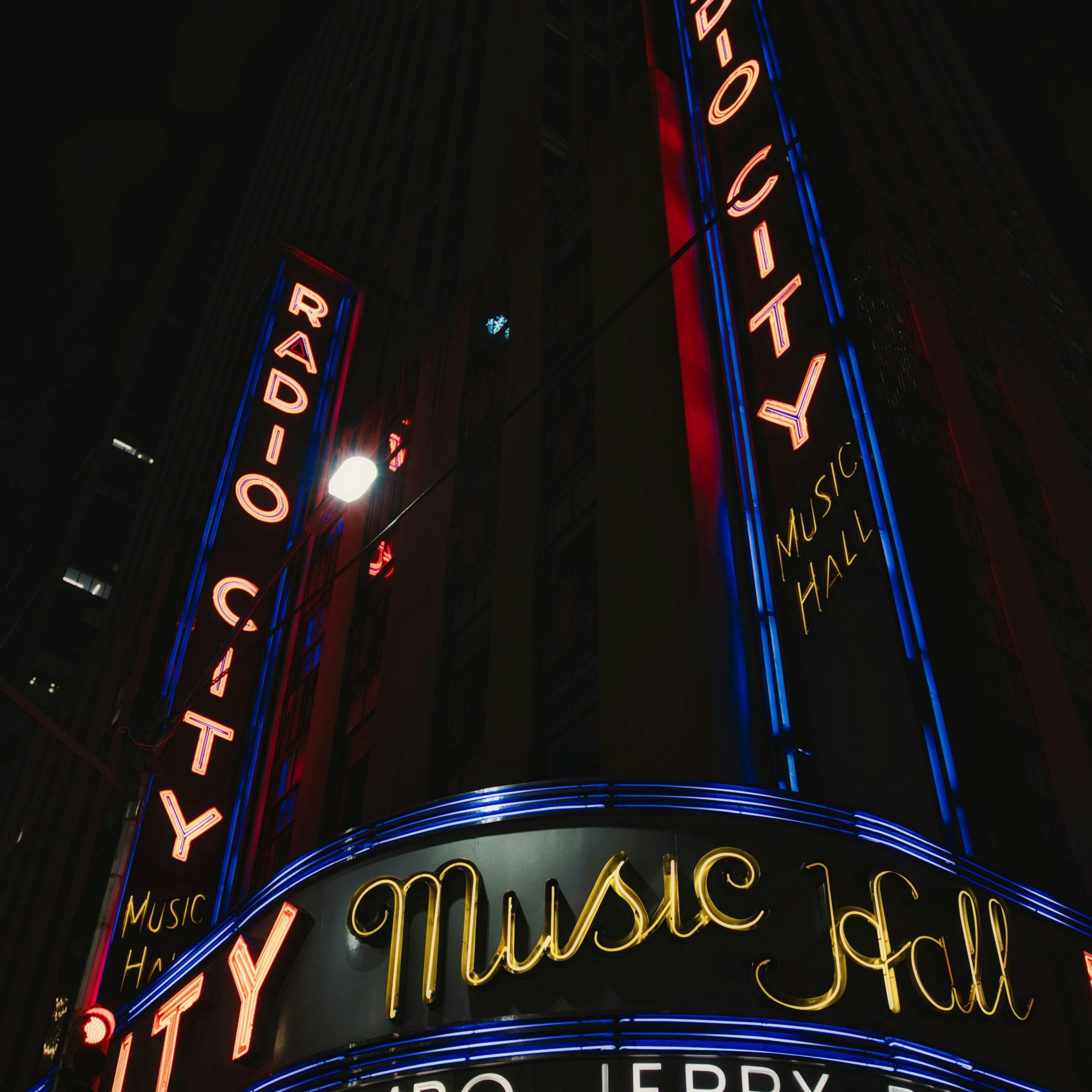 Radio City Music Hall neon marquee at night in Midtown Manhattan with illuminated Art Deco signage and street-level glow