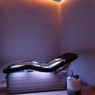 Minimalist spa room with contoured therapy bed and ambient lighting, evoking futuristic calm and sensory refinement