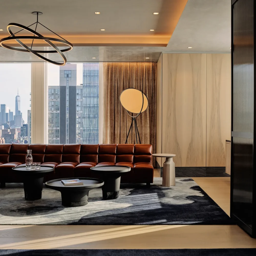 Luxurious living room with leather sectional, city views, and sculptural lighting, evoking urban sophistication and relaxed elegance