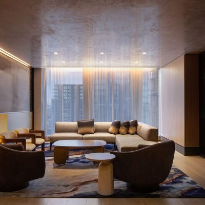 Luxurious living room at Equinox Hotel with beige sectional, fireplace and city view through tall windows