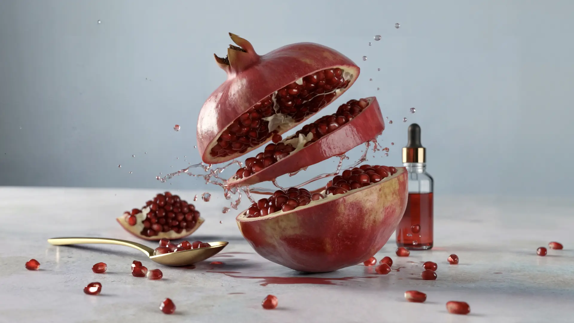A sliced pomegranate mid-air with splashing juice next to a glass dropper bottle and a gold spoon holding seeds.