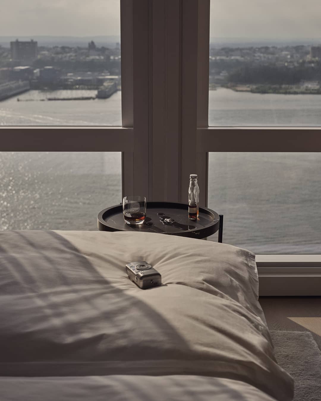 equinox hotel room closeup of bed in front of floor to ceiling windows showing river view