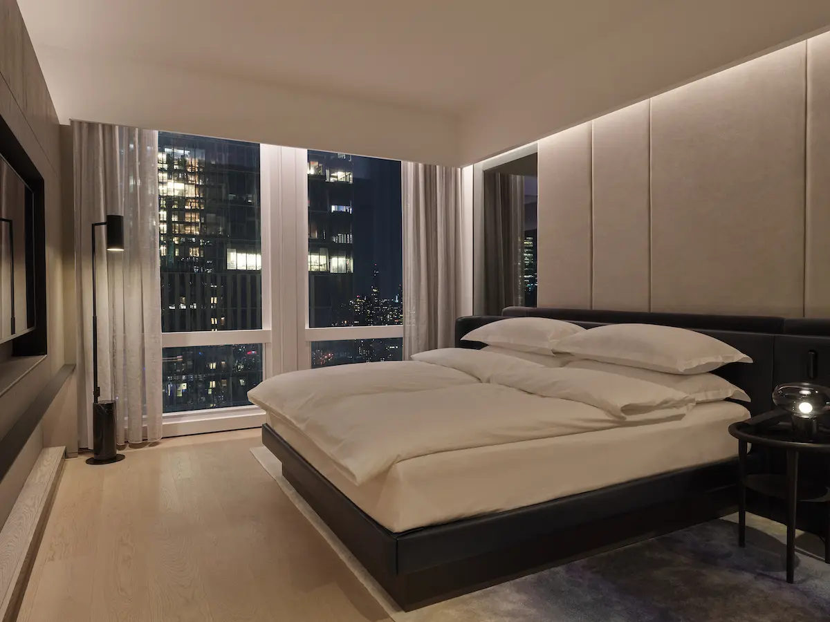 equinox hotel room king bed with city skyline seen through window