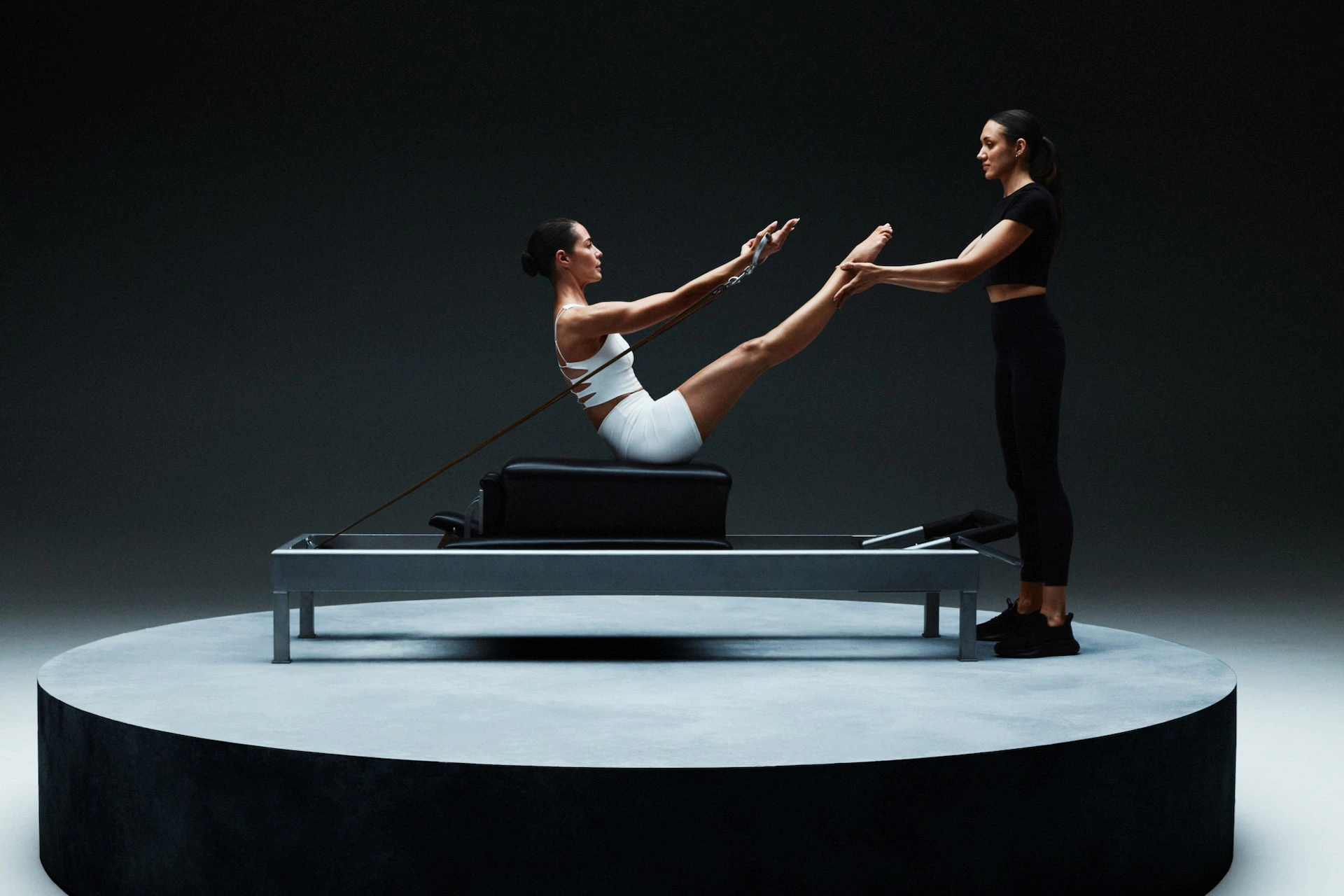 Woman performing Pilates on reformer with trainer at Equinox Hotel fitness center