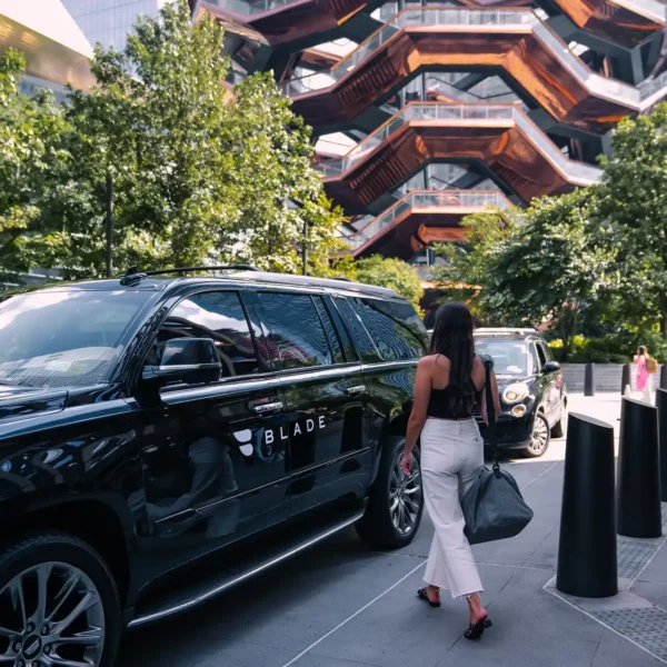 Woman exiting Equinox Hotel NYC to board private car for exclusive BLADE experience.