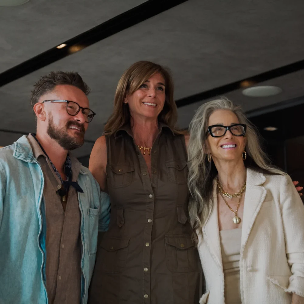 Catharine Arnston posing with two guests at wellness event, all smiling in modern indoor setting