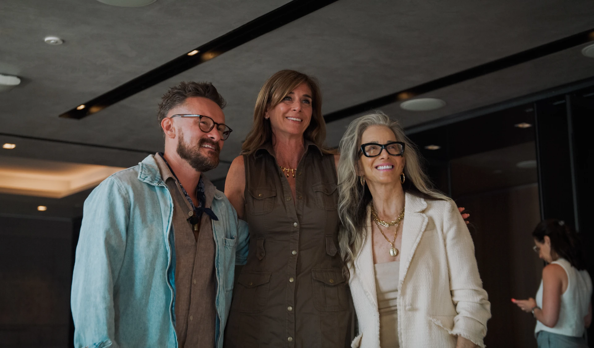 Catharine Arnston posing with two guests at wellness event, all smiling in modern indoor setting