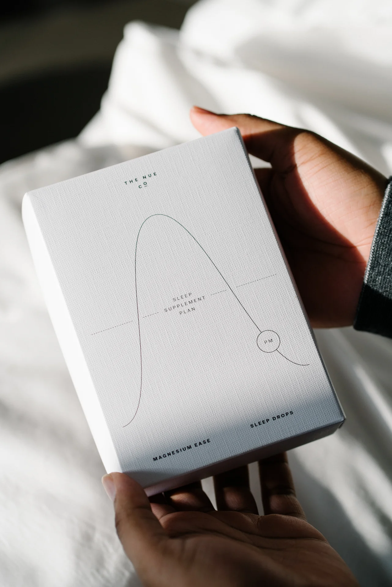 Guest holding box of The Nue Co. Sleep Drops, featuring minimalist design and magnesium-based sleep supplement plan