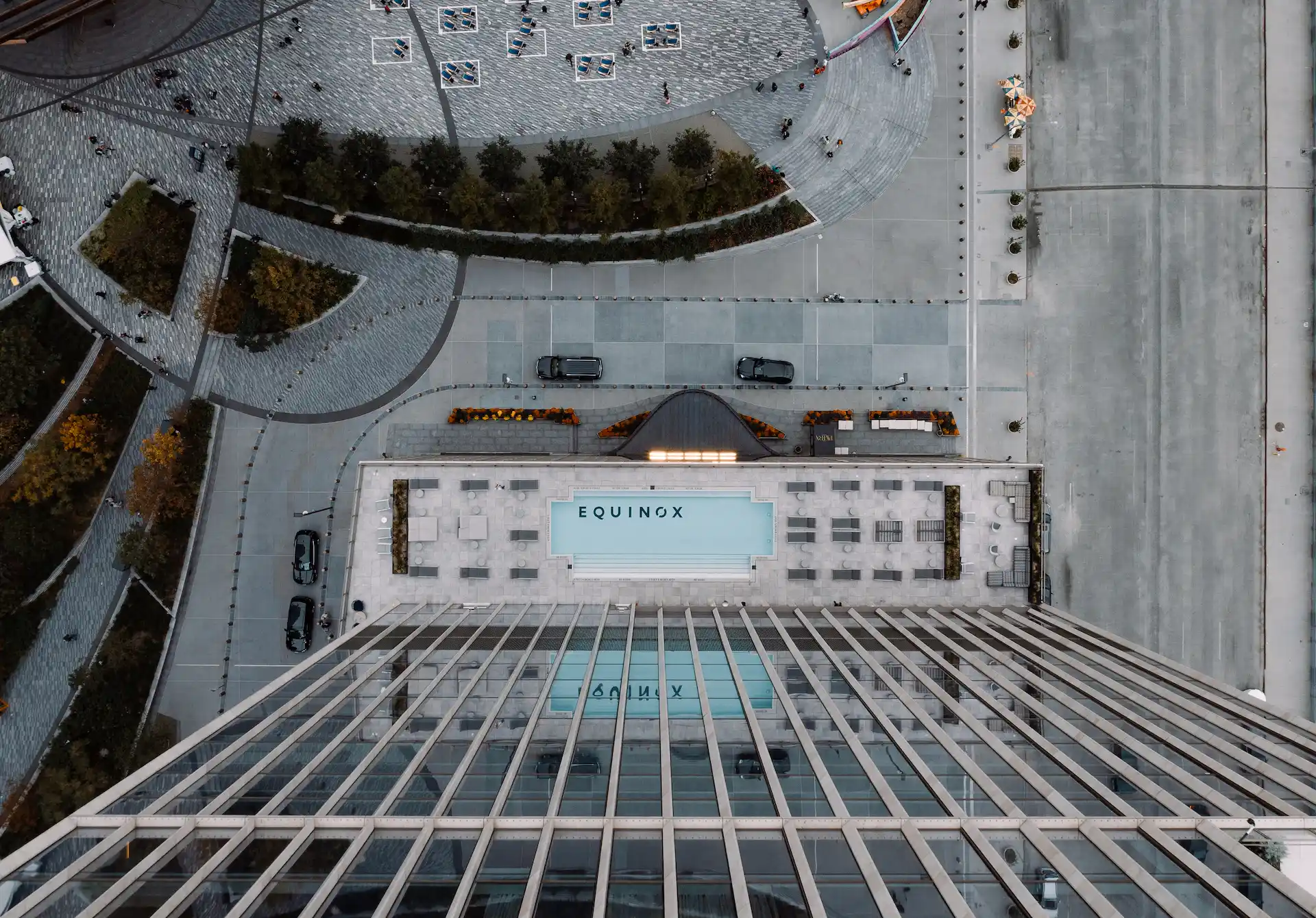 Aerial view of Equinox rooftop with pools, lounge chairs, and geometric plaza below in NYC.