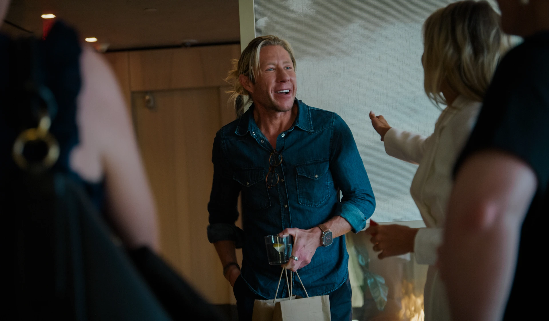 Dr. Matthew Walker smiling and holding a drink during casual conversation at indoor gathering
