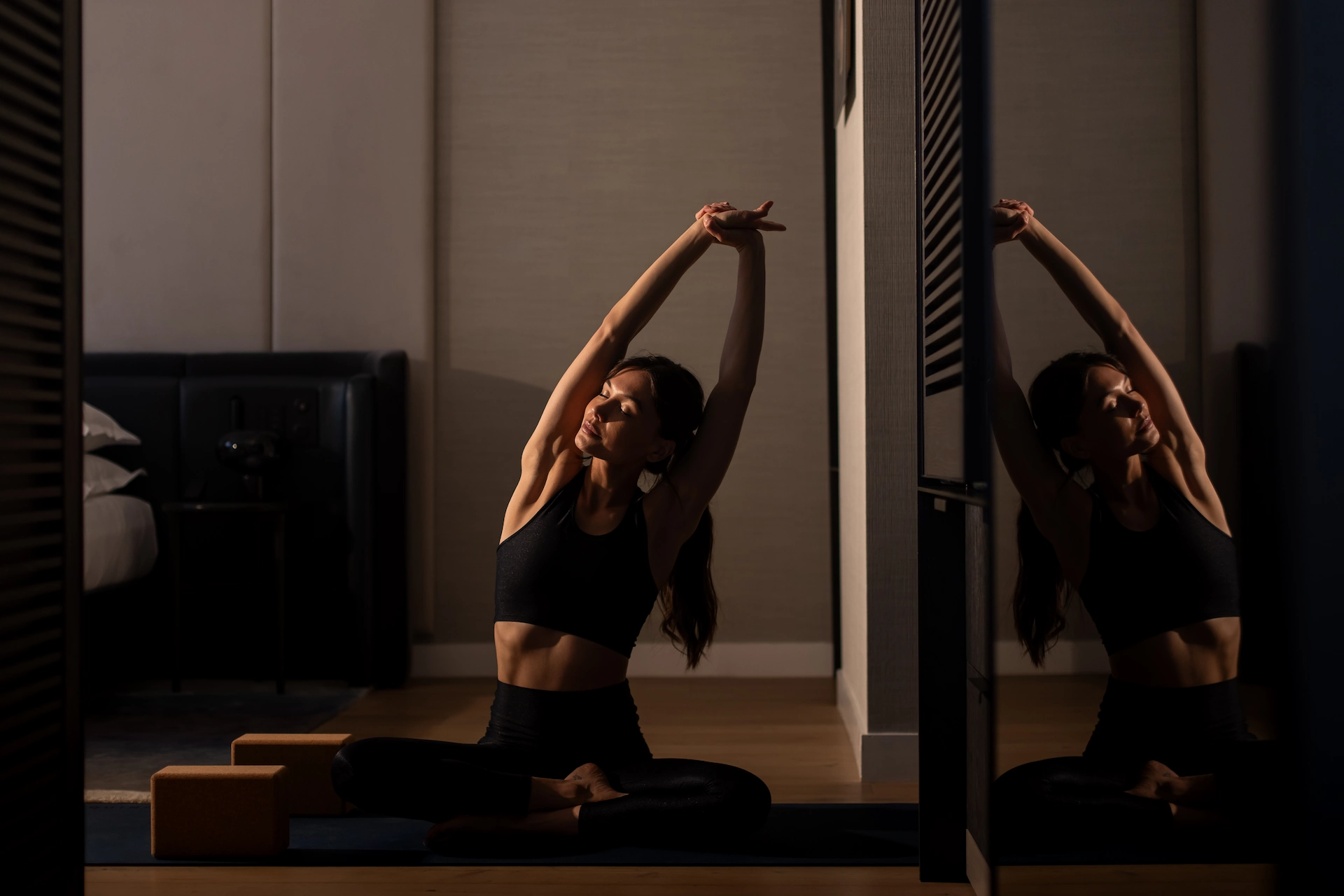 Private indoor yoga session with seated side stretch, reflected in mirror, highlighting Equinox’s focus on mindful movement.