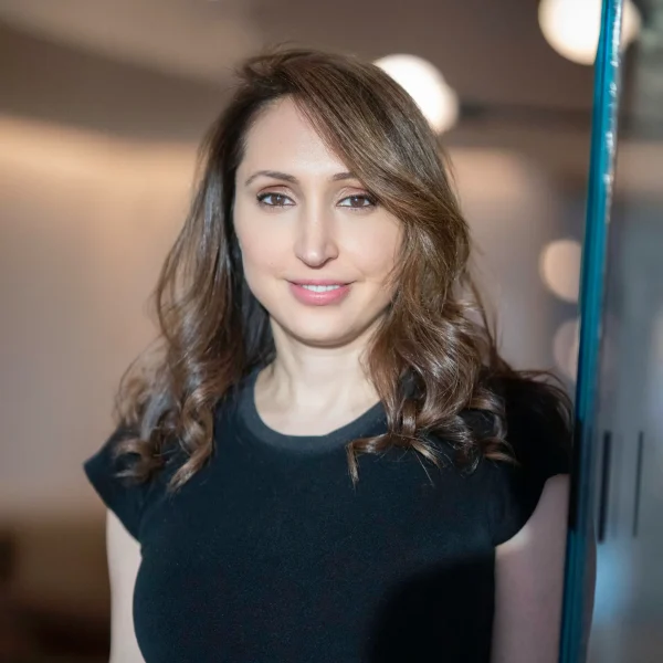 Ara Patterson, VP Food & Beverage + Spa Innovation, standing indoors near glass surface with softly lit background