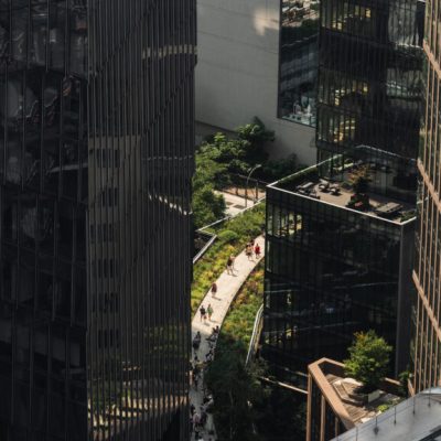 Elevated urban walkway with greenery surrounded by glass buildings and pedestrians in modern cityscape