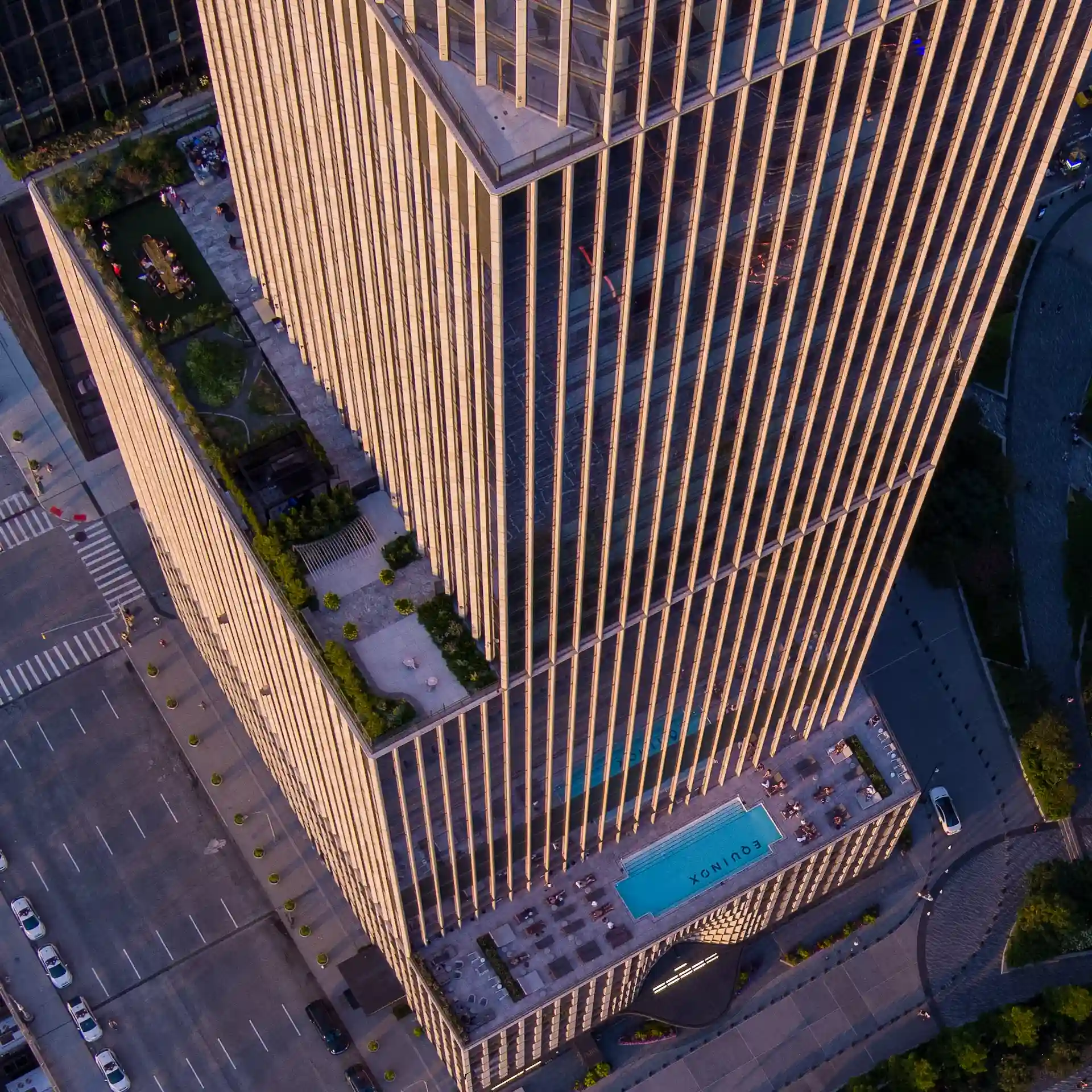 Aerial view of Equinox rooftop pool with lounge chairs, landscaped terrace, and sleek high-rise facade