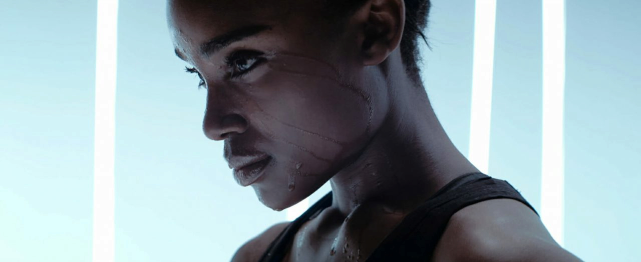 Side profile of person with water streaming down face and neck in cool-toned wellness studio setting