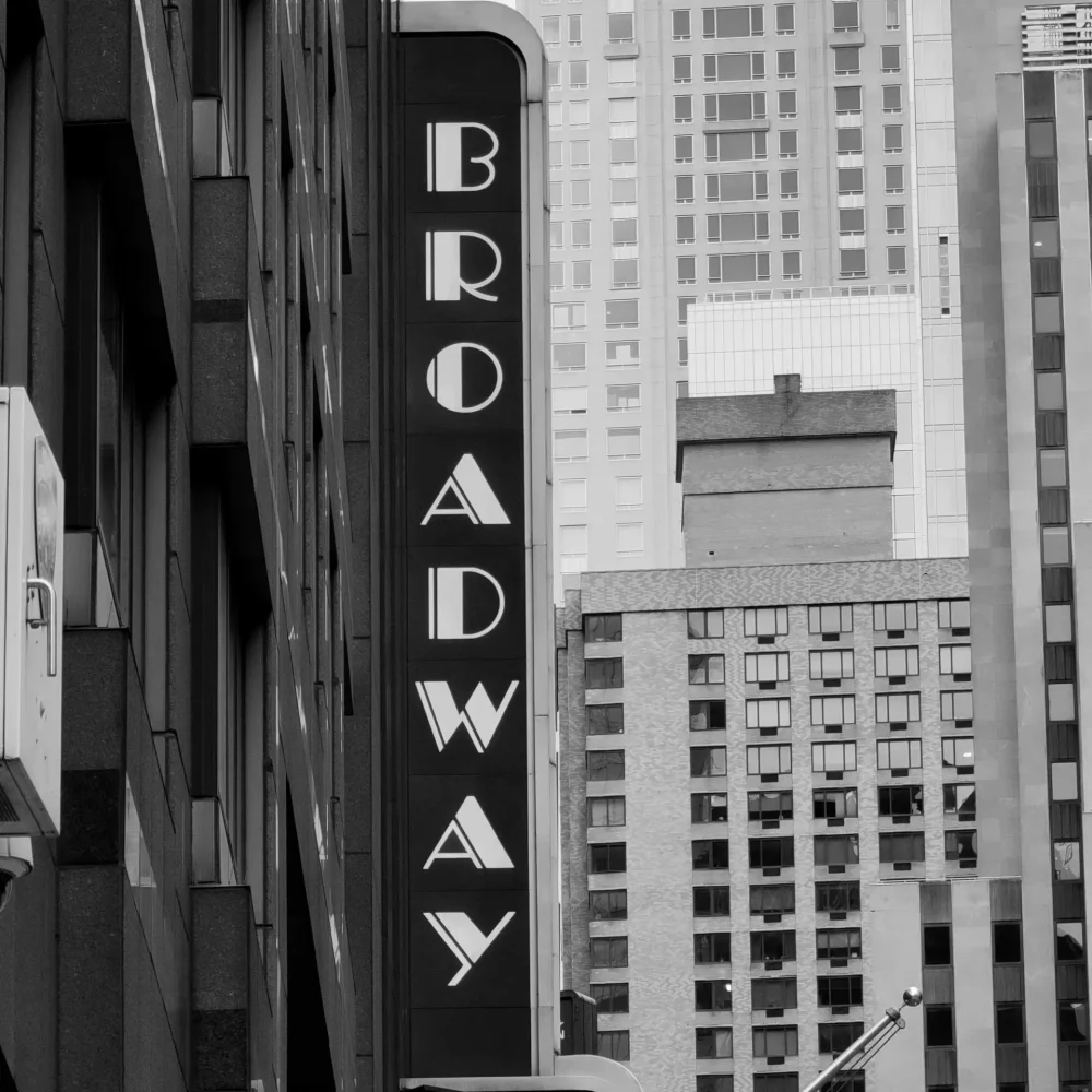 Vertical BROADWAY sign on building facade in black and white urban scene with classic NYC architecture