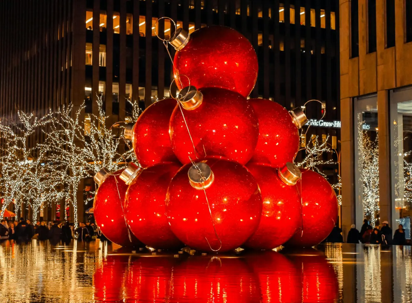 Stacked red Christmas ornaments in city plaza with festive lights, wet reflections and McGraw-Hill building