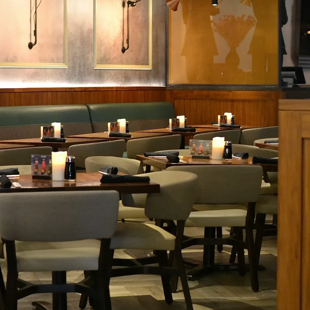 Equinox restaurant interior with beige chairs, candlelit tables, fan silhouettes, and wood-paneled walls