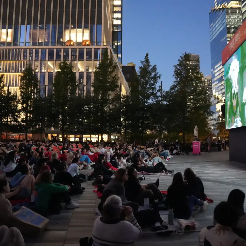 Outdoor movie screening at Brookfield Place with seated crowd, city buildings and evening sky