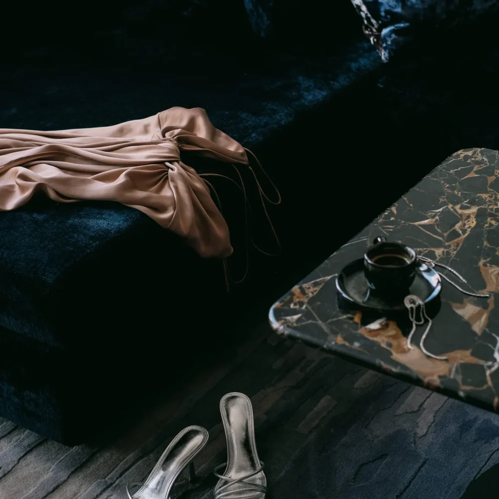 Velvet couch with pink dress, metallic heels, and tea on marble table in intimate luxury setting