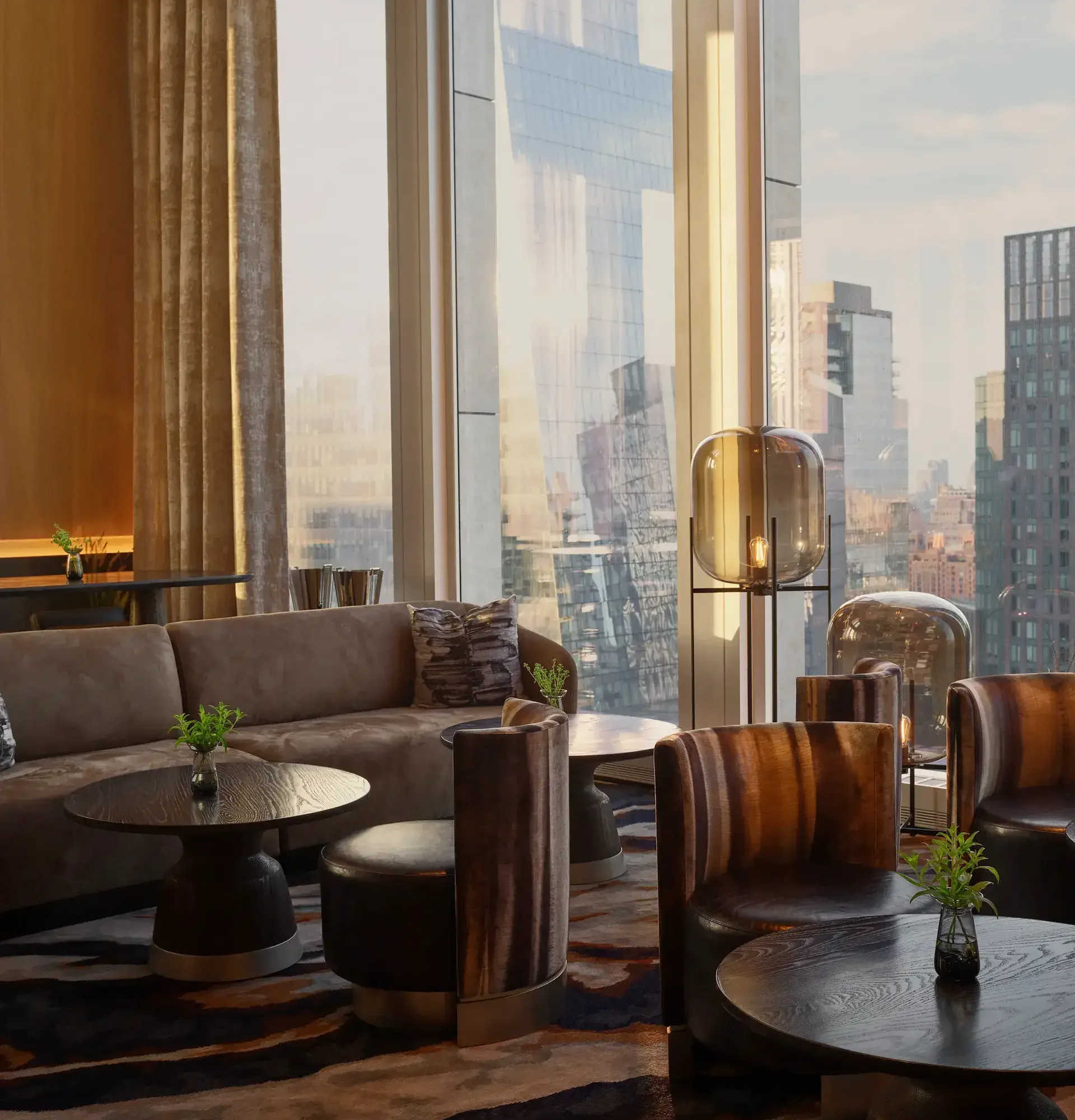 Upscale lounge with curved armchairs, abstract carpet, and floor-to-ceiling windows overlooking cityscape