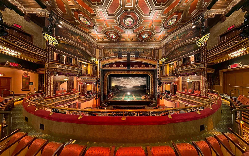 Broadway Theater interior with ornate ceiling, murals, red velvet seating, and scenic stage view from balcony